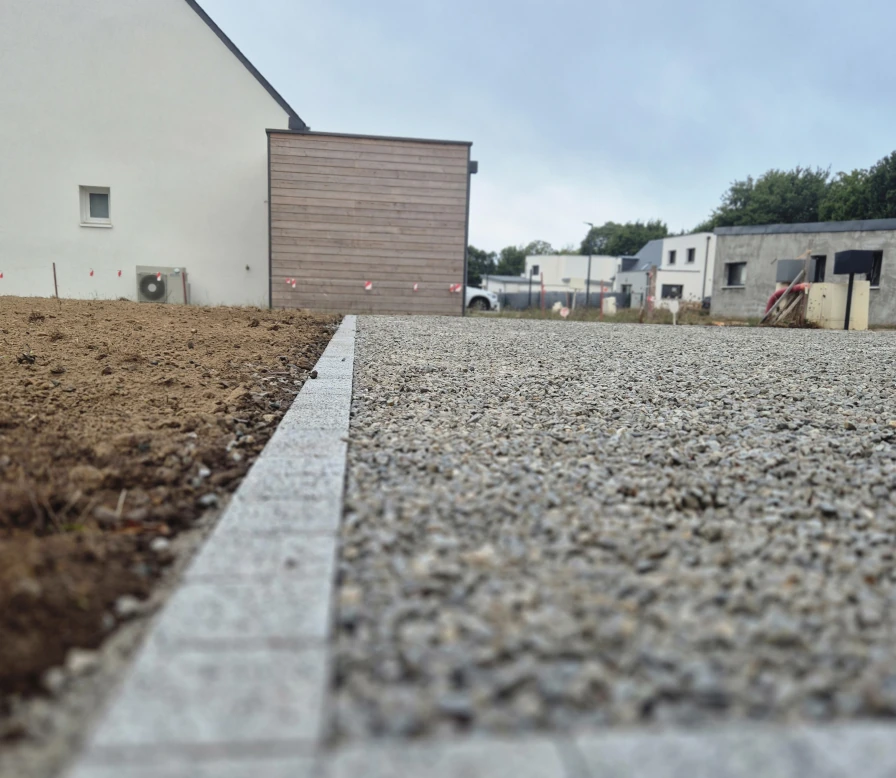 Pose de bordures en pierre délimitant une allée gravillonnée devant une maison neuve à Quimperlé
